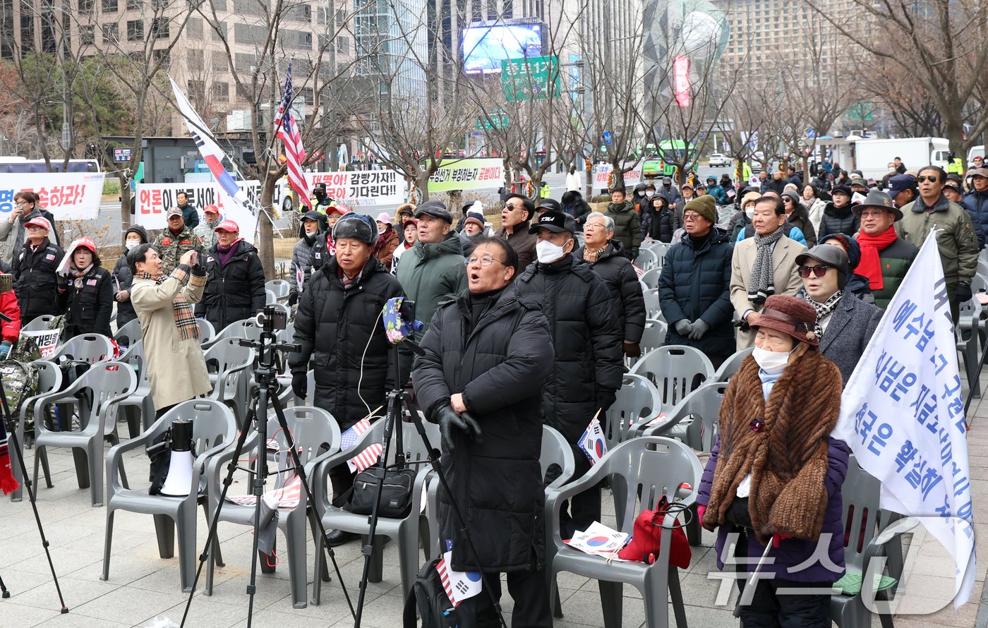 16일 서울 중구 동화면세점 앞에서 열린 자유통일당 탄핵반대 집회에서 참가자들이 애국가를 부르고 있다. 맨 앞에는 집회 생중계용 삼각대와 핸드폰이 설치돼 있다. 2024.12.16/뉴스1 ⓒ News1 김명섭 기자