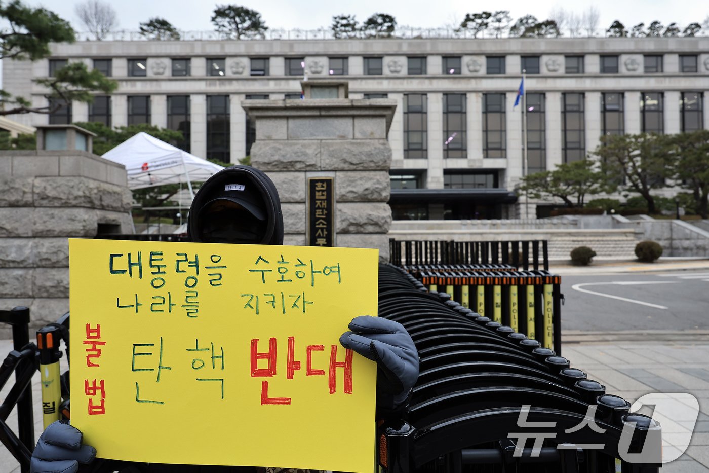 윤석열 대통령에 대한 본격적인 탄핵심판절차에 돌입한 16일 오후 서울 종로구 재동 헌법재판소 앞에서 &#39;대통령을 수호하여 나라를 지키자, 불법 탄핵 반대&#39; 손피켓을 든 시민이 탄핵 반대 1인 시위를 하고 있다. 2024.12.16/뉴스1 ⓒ News1 박정호 기자