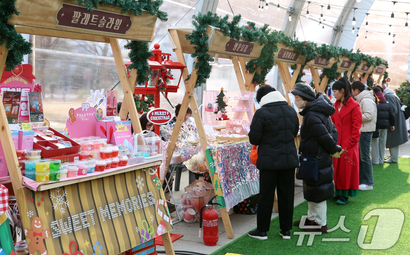 본문 이미지 - 20일 서울 여의도한강공원 이벤트광장에서 열린 로맨틱 한강 크리스마스 마켓에서 시민들이 부스를 살펴보고 있다. 크리스마스 선물을 살 수 있는 60개 상점으로 구성된 ‘더 로맨틱 하우스’가 들어서고, ‘눈사람의 공방’에서는 공예품 만들기 체험도 할 수 있다. 이곳에 마련된 ‘진저 브래드 쿠키의 화실’에서는 아름다운 빛 조형물을 감상할 수 있다.2024.12.20/뉴스1 ⓒ News1 김명섭 기자