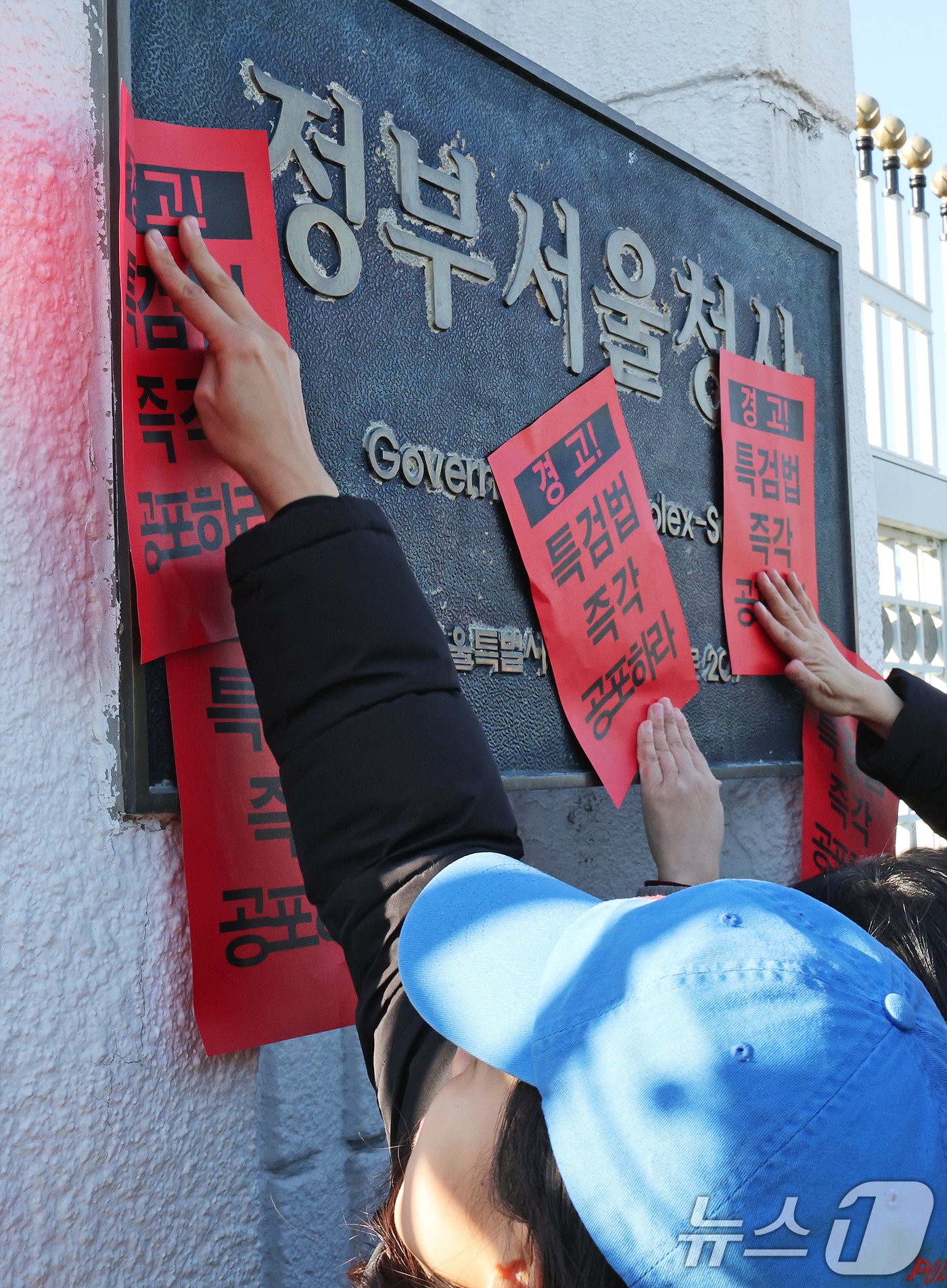 참여연대 회원들이 23일 오후 서울 종로구 정부서울청사에서 한덕수 대통령 권한대행 국무총리을 향해 내란 특검법 및 김건희 특검법 즉각 공포를 촉구하는 경고장을 현판에 부착하고 있다. 2024.12.23/뉴스1 ⓒ News1 장수영 기자