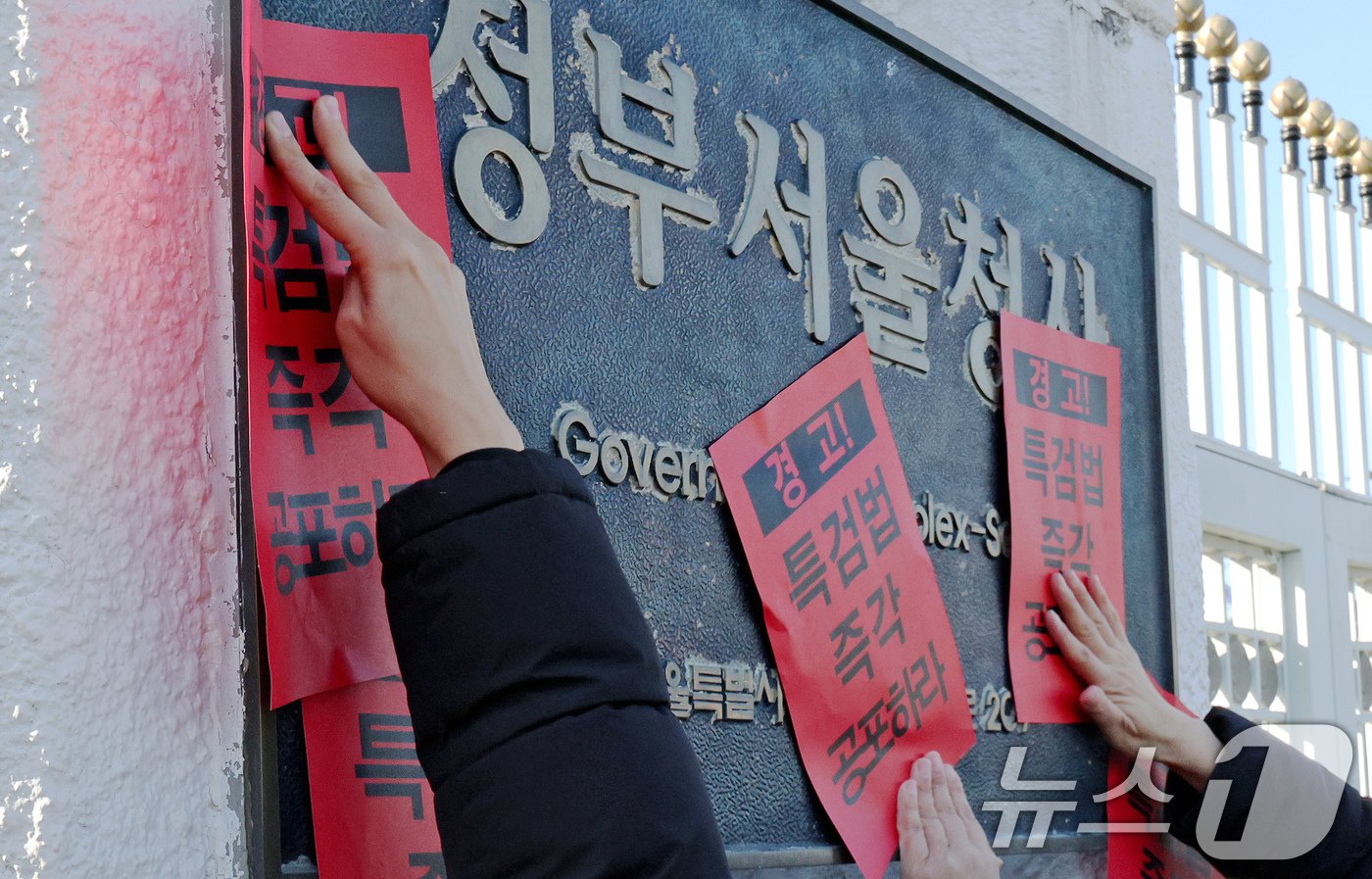 참여연대 회원들이 23일 오후 서울 종로구 정부서울청사에서 한덕수 대통령 권한대행 국무총리을 향해 내란 특검법 및 김건희 특검법 즉각 공포를 촉구하는 경고장을 현판에 부착하고 있다. 2024.12.23/뉴스1 ⓒ News1 장수영 기자