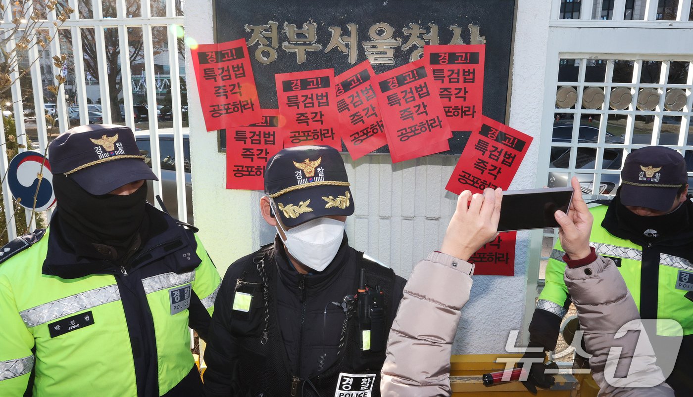 참여연대 회원들이 23일 오후 서울 종로구 정부서울청사에서 한덕수 대통령 권한대행 국무총리을 향해 내란 특검법 및 김건희 특검법 즉각 공포를 촉구하는 경고장을 현판에 부착하고 있다. 2024.12.23/뉴스1 ⓒ News1 장수영 기자