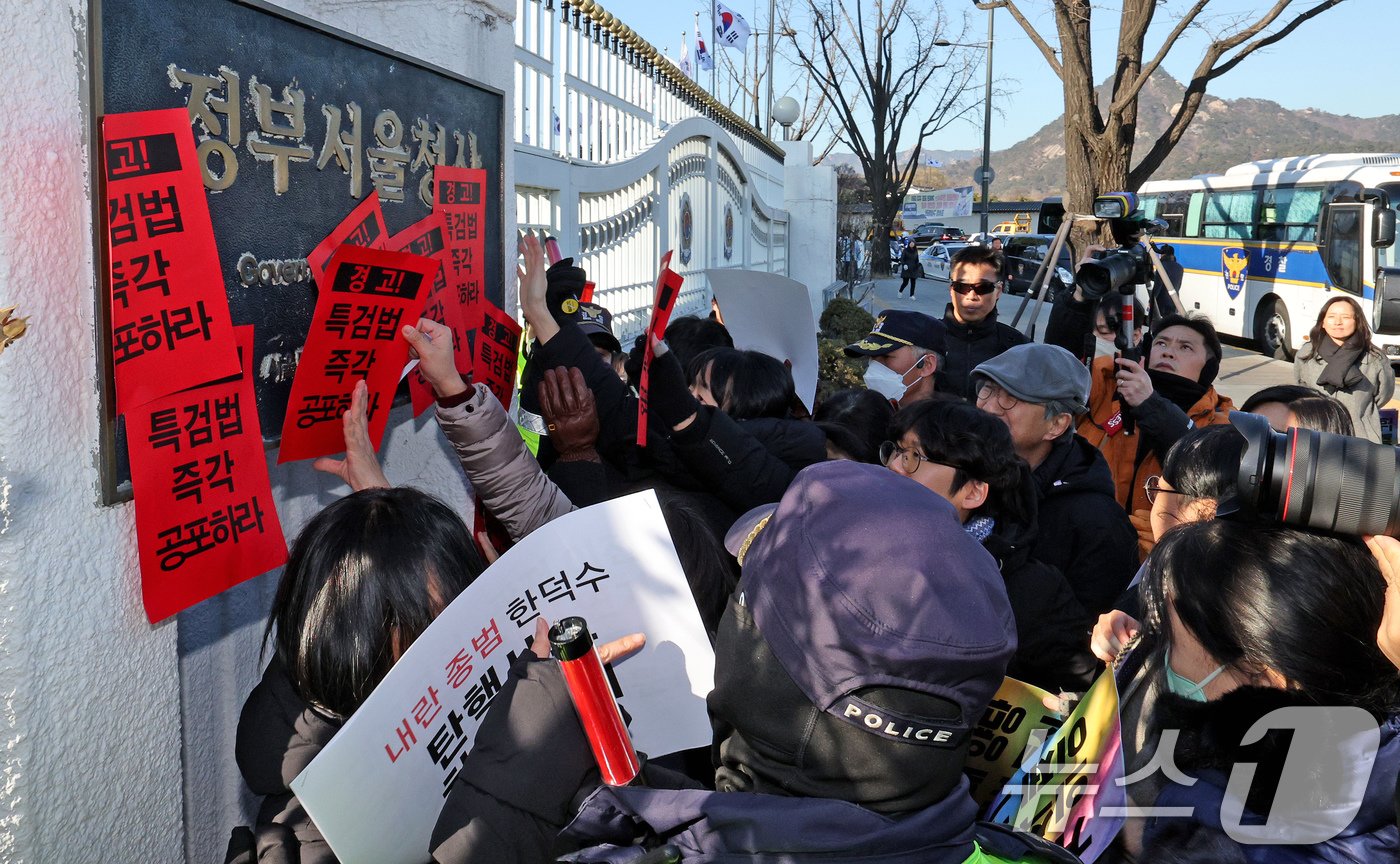 참여연대 회원들이 23일 오후 서울 종로구 정부서울청사에서 한덕수 대통령 권한대행 국무총리을 향해 내란 특검법 및 김건희 특검법 즉각 공포를 촉구하는 경고장을 현판에 부착하고 있다. 2024.12.23/뉴스1 ⓒ News1 장수영 기자