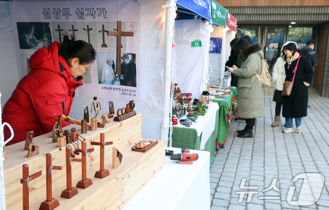 (서울=뉴스1) 김명섭 기자 = 24일 서울 명동성당 가톨릭회관 앞 광장에서 열린 '2024 명동, 겨울을 밝히다' 축제 성탄마켓에서 시민과 신자들이 수공예 성물, 생황 공예품 등 …