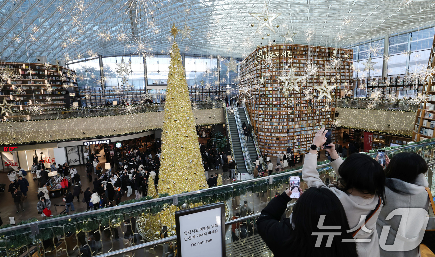 (서울=뉴스1) 박세연 기자 = 크리스마스 이브인 24일 대형 트리 등 크리스마스 장식으로 꾸며진 서울 강남구 스타필드 코엑스몰 별마당도서관을 찾은 시민이 기념사진을 찍고 있다. …