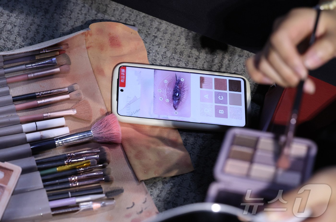 본문 이미지 -  동춘서커스 곡예사가 화장법을 보며 직접 분장하는 모습.  화려한 무대 뒤에서 자신을 꾸미는 이 과정 역시 그들의 꿈을 향한 열정을 엿볼 수 있는 중요한 순간이다.  ⓒ News1 박지혜 기자