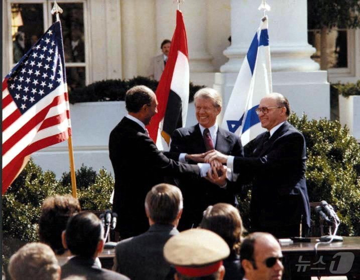 본문 이미지 - 제39대 미국 대통령을 지낸 지미 카터 전 대통령이 29일&#40;현지시간&#41; 향년 100세의 나이로 별세했다. 사진은 카터 당시 미국 대통령&#40;가운데&#41;과 안와르 사다트 당시 이집트 대통령, 메나헴 베긴 당시 이스라엘 총리가 1979년 3월 26일 백악관에서 이집트와 이스라엘 간 평화 협정에 서명한 뒤 서로 손을 잡고 있는 모습. ⓒ 로이터=뉴스1 ⓒ News1 최종일 기자