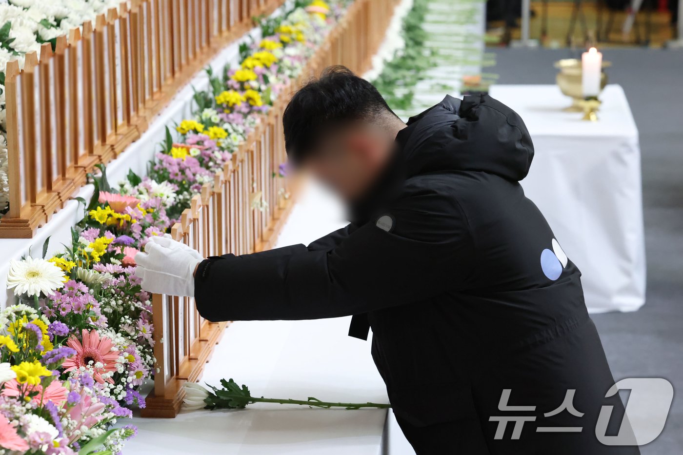 본문 이미지 - 제주항공여객기참사 발생 이틀째인 30일 전남 무안 스포츠파크에 차려진 합동 분향소에서 한 시민이 조문 도중 위패를 잡고 있다. &#40;공동취재&#41; 2024.12.30/뉴스1 ⓒ News1 김민지 기자