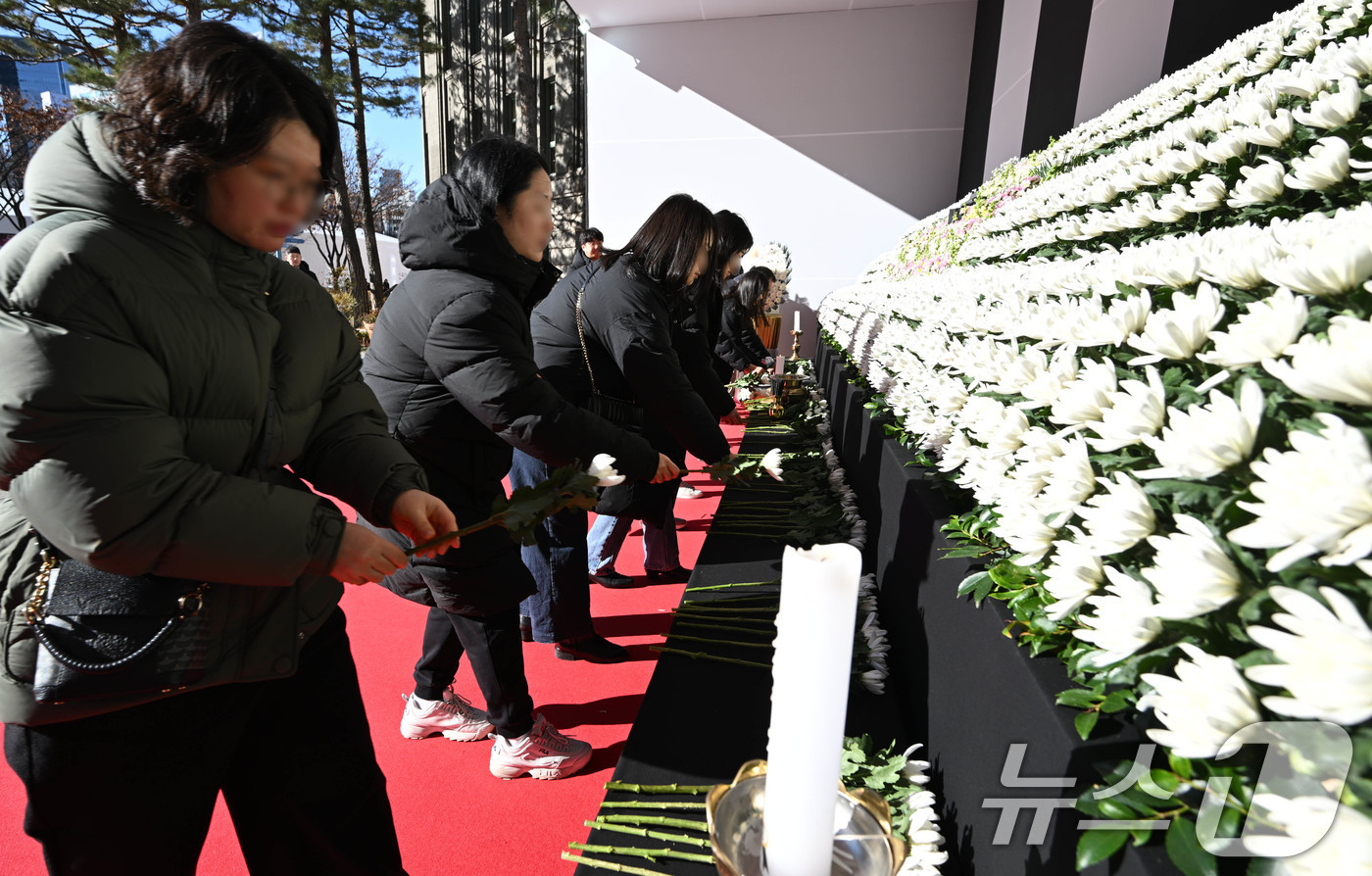 (서울=뉴스1) 이동해 기자 = 31일 오전 서울시청 본관 앞에 마련된 제주항공 여객기 희생자 합동분향소를 찾은 시민들이 헌화하고 있다. (공동취재)2024.12.31/뉴스1