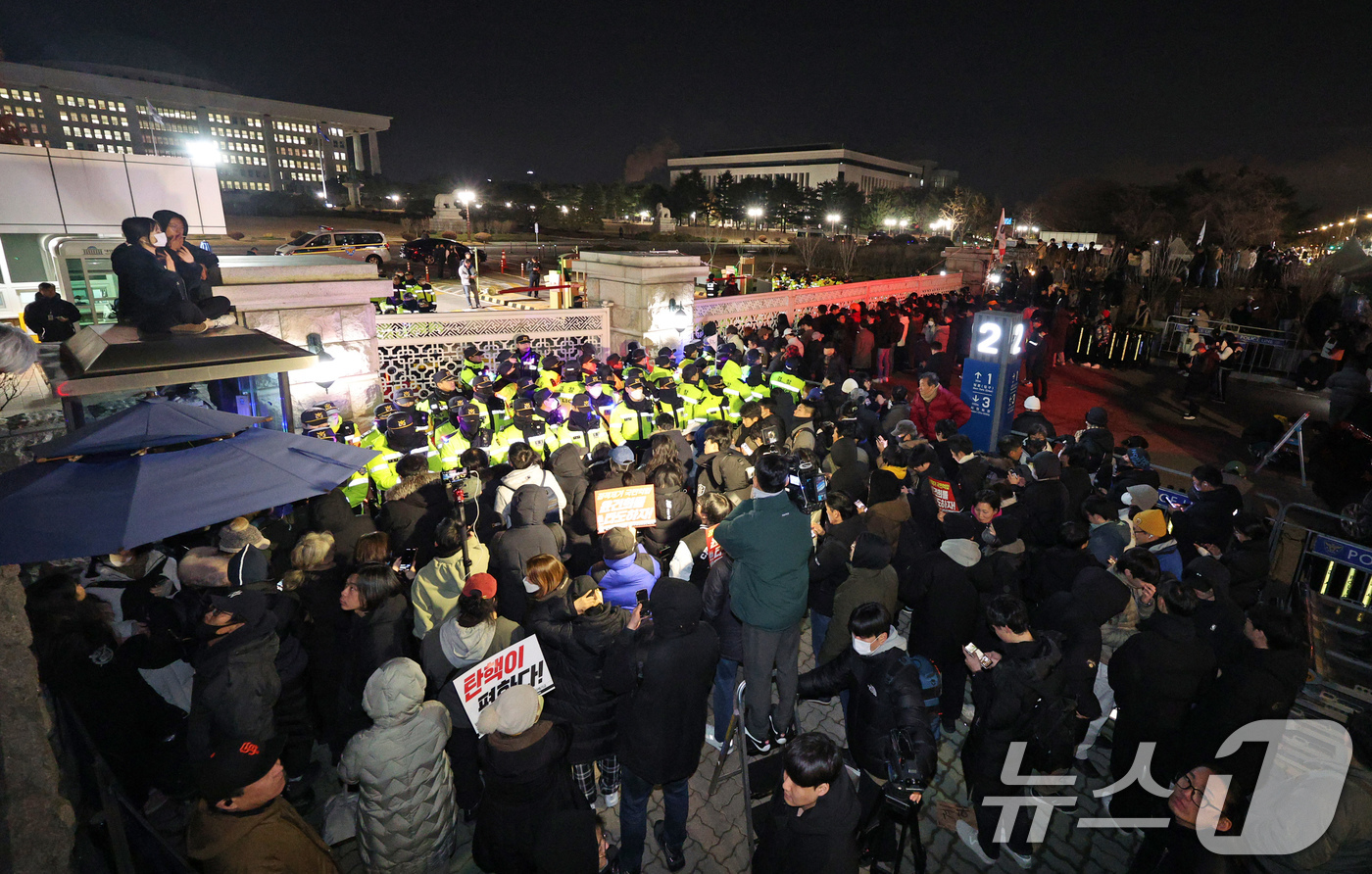 (서울=뉴스1) 장수영 기자 = 윤석열 대통령의 비상계엄 해제 요구 결의안이 국회 본회의에서 통과된 4일 새벽 서울 여의도 국회 정문 앞에 모인 시민들이 윤 대통령을 규탄하고 있다 …