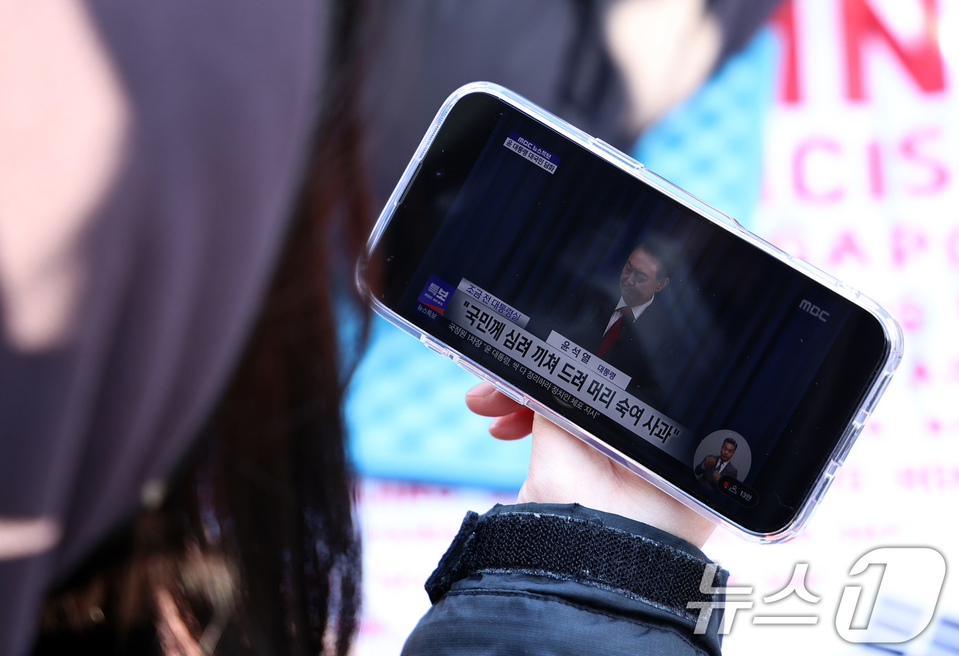 (서울=뉴스1) 구윤성 기자 = 7일 오전 서울 여의도 국회 앞에서 윤석열 대통령의 탄핵을 촉구하며 농성중인 시민이 스마트폰으로 대통령 대국민담화를 시청하고 있다. 2024.12. …