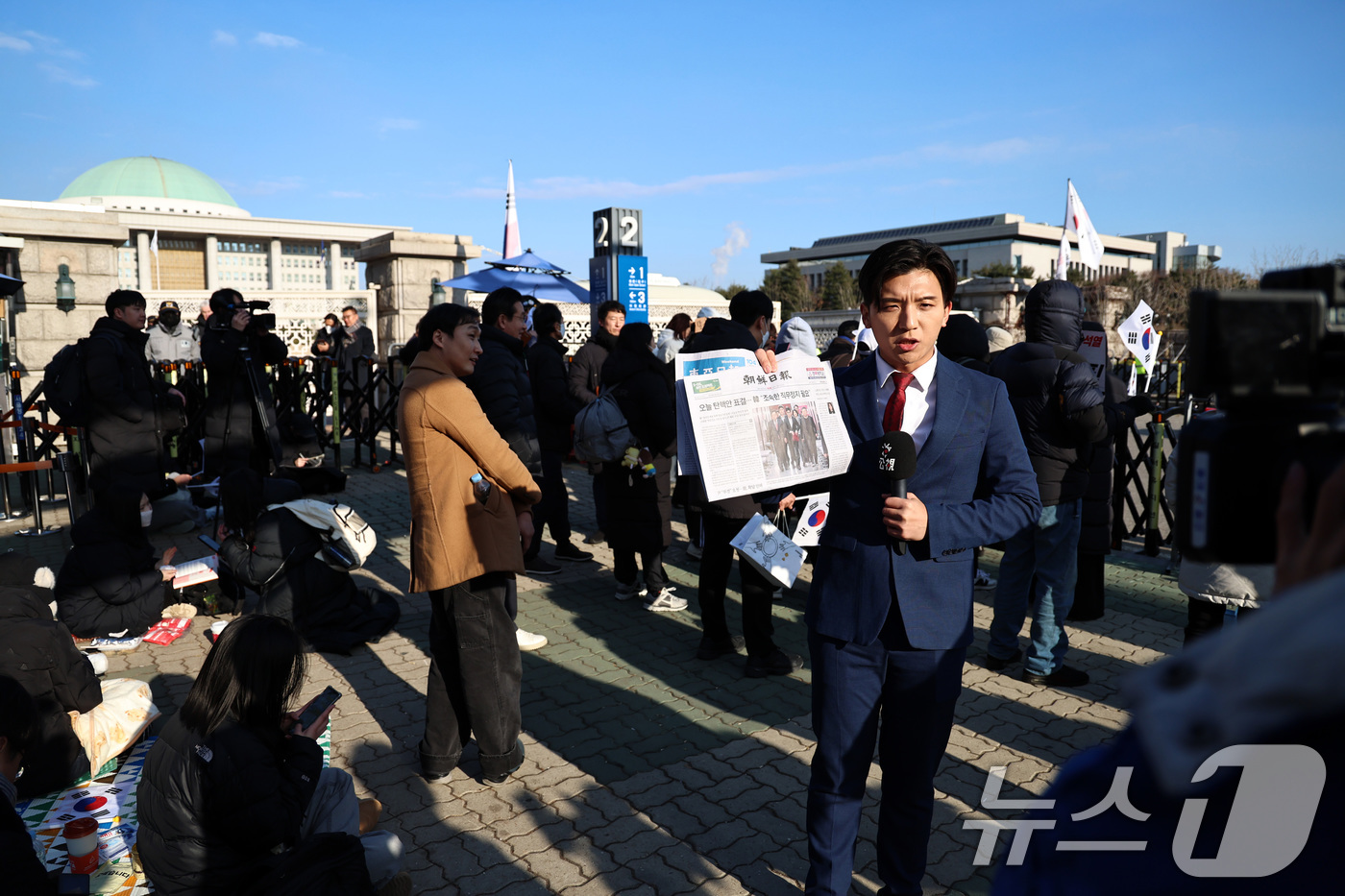 (서울=뉴스1) 구윤성 기자 = 윤석열 대통령에 대한 탄핵소추안 표결을 앞둔 7일 오전 서울 여의도 국회 앞에서 중국 외신기자가 국내 일간지를 들고 취재활동을 하고 있다. 2024 …