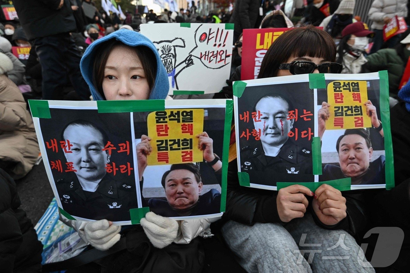 2024년 12월 7일 밤 서울 국회 밖에서 윤석열 대통령의 탄핵을 주장하는 시위대가 직접 만든 손팻말을 들고 있다. ⓒ AFP=뉴스1