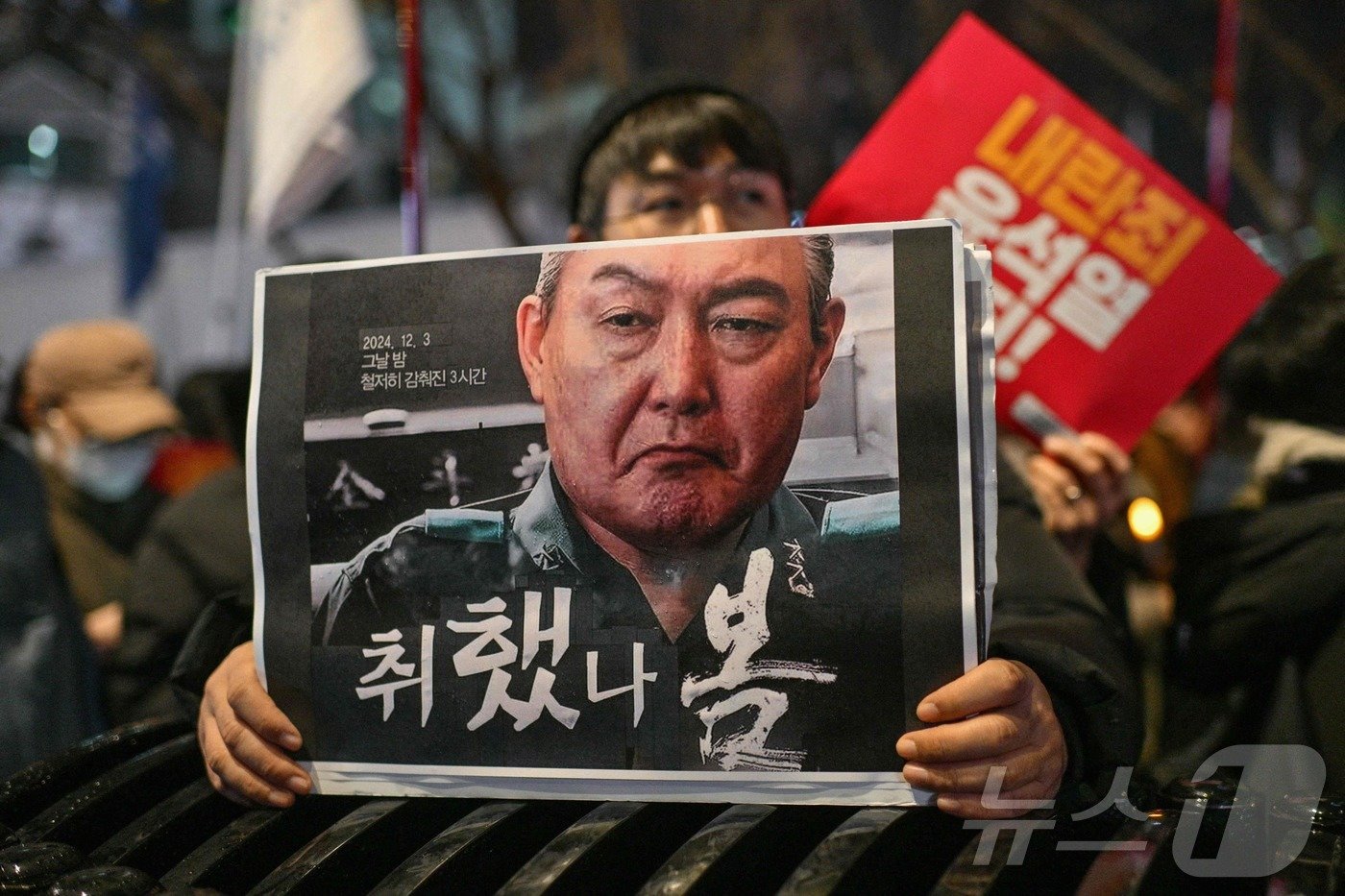 본문 이미지 - 2024년 12월 5일 서울 광화문에서 열린 대통령 퇴진을 촉구하는 촛불집회에서 한 시위자가 직접 만든, 윤석열 한국 대통령의 이미지가 담긴 포스터를 들고 있다. ⓒ AFP=뉴스1