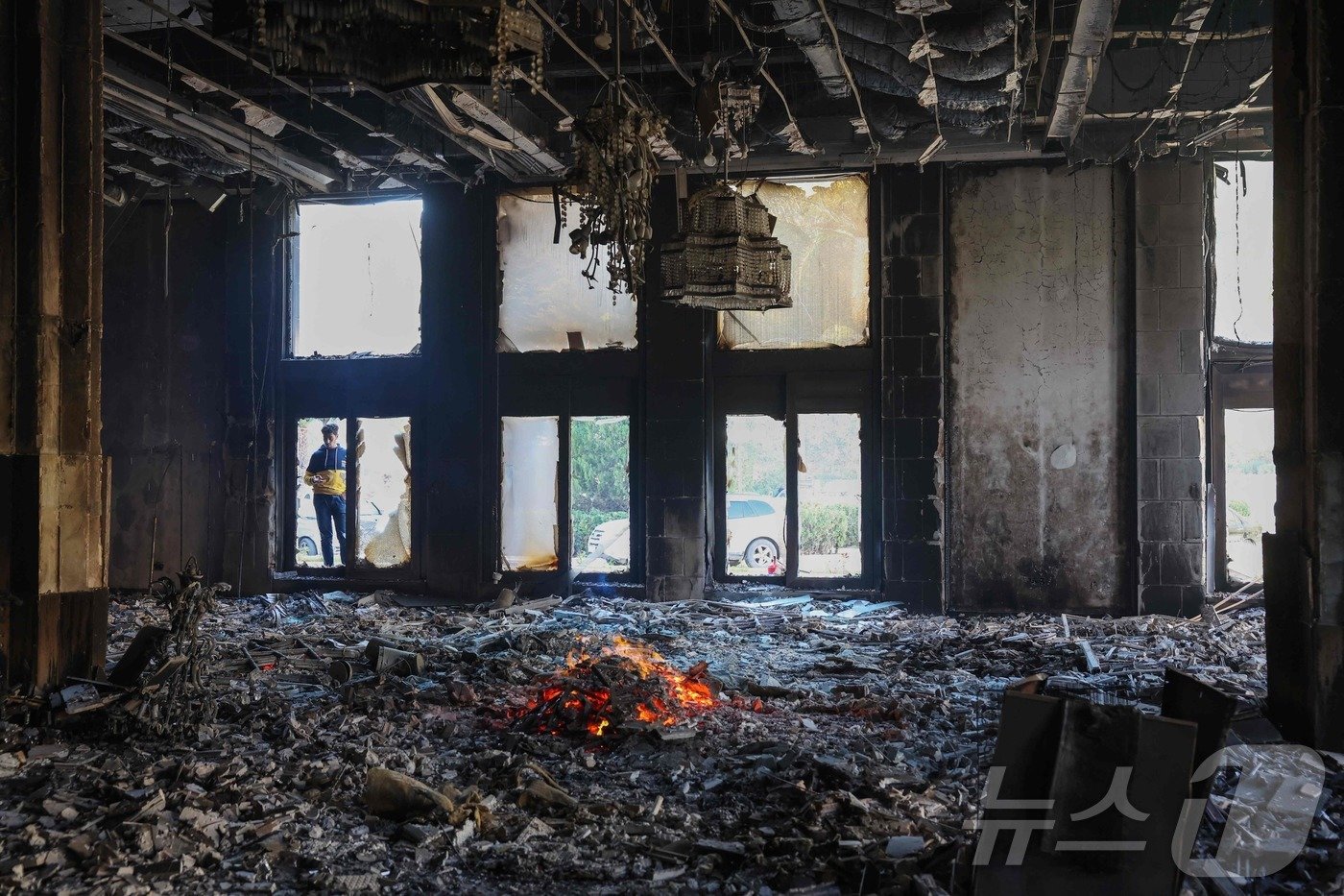 본문 이미지 - 8일&#40;현지시간&#41; 시리아 다마스쿠스 대통령궁의 한 방이 완전히 불탄 모습을 한 남성이 지켜보고 있다. 24년간 철권통치를 이어온 바샤르 알 아사드 시리아 대통령은 13년간의 내전 끝에 반군의 공세에 밀려 가족과 함께 시리아를 떠나 러시아 모스크바로 피신했다. 2024.12.08 ⓒ AFP=뉴스1 ⓒ News1 김지완 기자