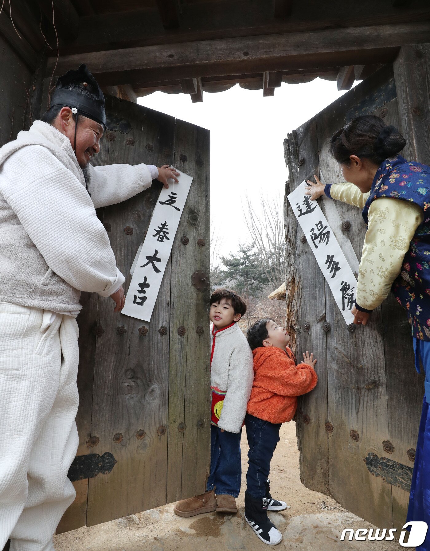 본문 이미지 - 절기상 입춘(立春)을 사흘 앞둔 1일 경기 용인시 기흥구 한국민속촌에서 직원들과 아이들이 입춘대길(立春大吉)과 건양다경(建陽多慶)이라고 적은 입춘첩을 대문에 붙이고 있다. 입춘대길과 건양다경은 '봄이 시작되니 크게 길하고 경사스러운 일이 많이 생기길 기원한다'는 의미를 갖고 있다. 2024.2.1/뉴스1 ⓒ News1 김영운 기자