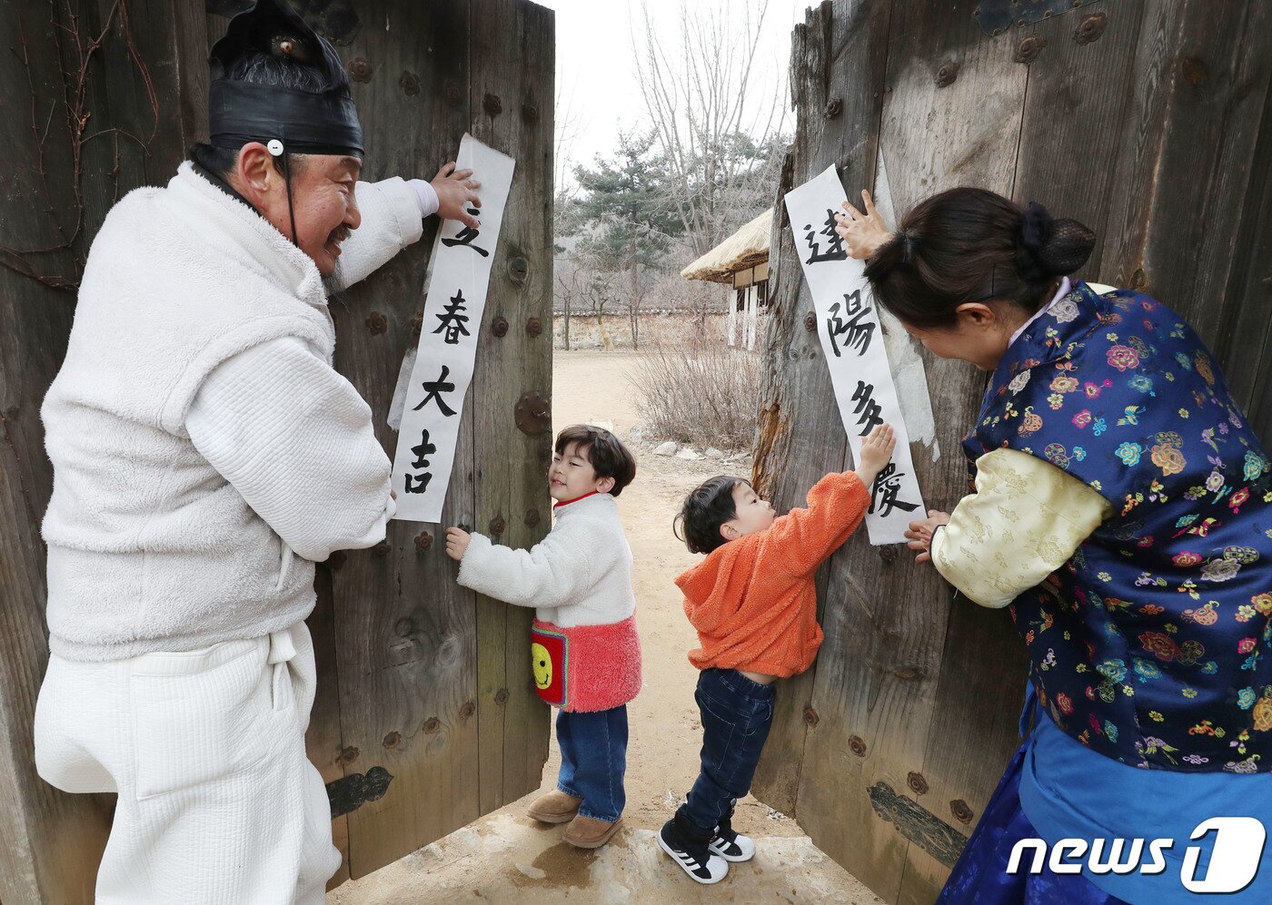 본문 이미지 - 절기상 입춘(立春)을 사흘 앞둔 1일 경기 용인시 기흥구 한국민속촌에서 직원들과 아이들이 입춘대길(立春大吉)과 건양다경(建陽多慶)이라고 적은 입춘첩을 대문에 붙이고 있다. 입춘대길과 건양다경은 '봄이 시작되니 크게 길하고 경사스러운 일이 많이 생기길 기원한다'는 의미를 갖고 있다. 2024.2.1/뉴스1 ⓒ News1 김영운 기자
