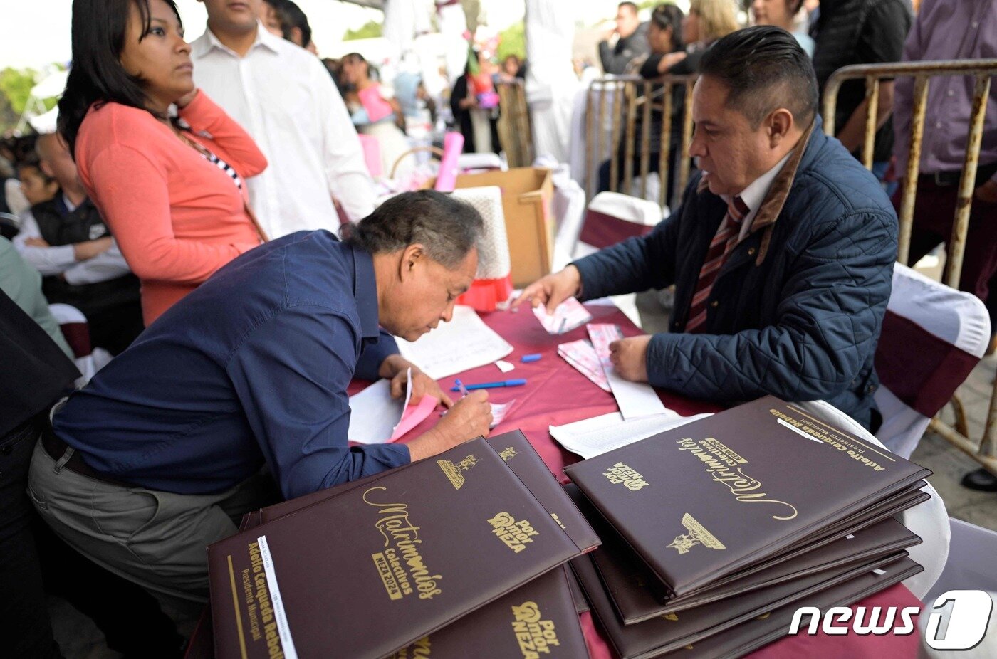 본문 이미지 - 밸런타인데이를 맞아 14일(현지시간) 멕시코의 수도 멕시코시티 외곽에 위치한 네사우알코요틀 마을에서 1200쌍의 합동 결혼식이 열린 가운데 한 남성이 혼인 증명서에 서명을 하고 있다. 2024.02.14 ⓒ AFP=뉴스1 ⓒ News1 정지윤 기자