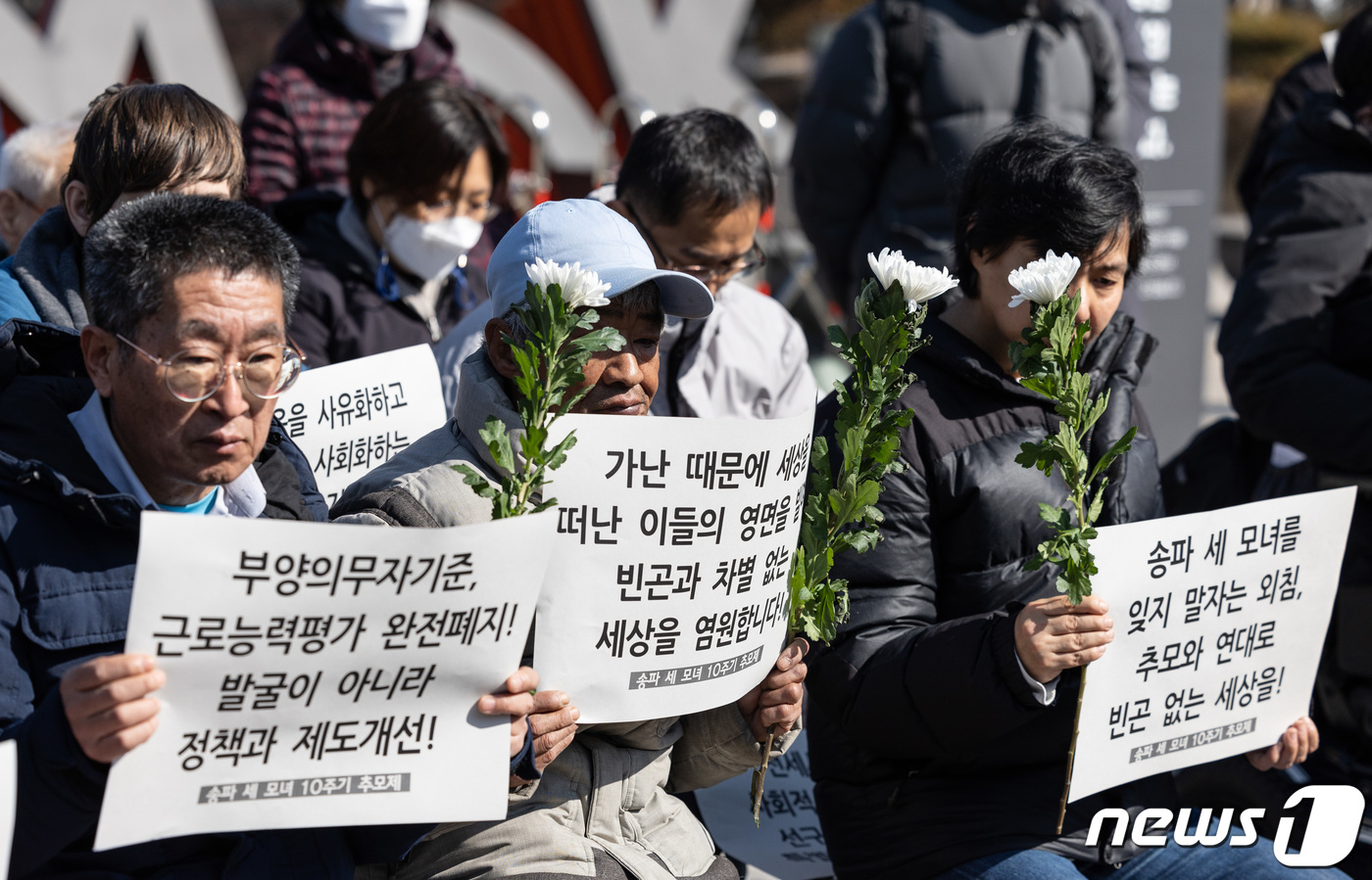 (서울=뉴스1) 이재명 기자 = 26일 오전 서울 용산구 전쟁기념관 앞에서 열린 송파 세 모녀 10주기 추모제에서 참석자들이 손 피켓을 들고 있다. 2024.2.26/뉴스1