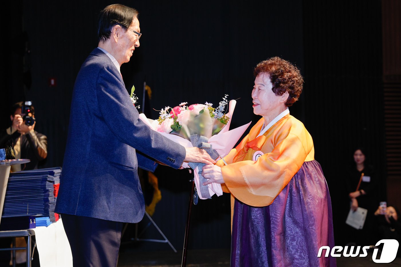 본문 이미지 - 27일 오전 서울 마포아트센터에서 열린 일성여자중고교 졸업식에서 최고령 졸업생인 김재술(88) 어르신이 이선재 교장으로부터 꽃다발을 받고 있다. 2024.2.27/뉴스1 ⓒ News1 안은나 기자