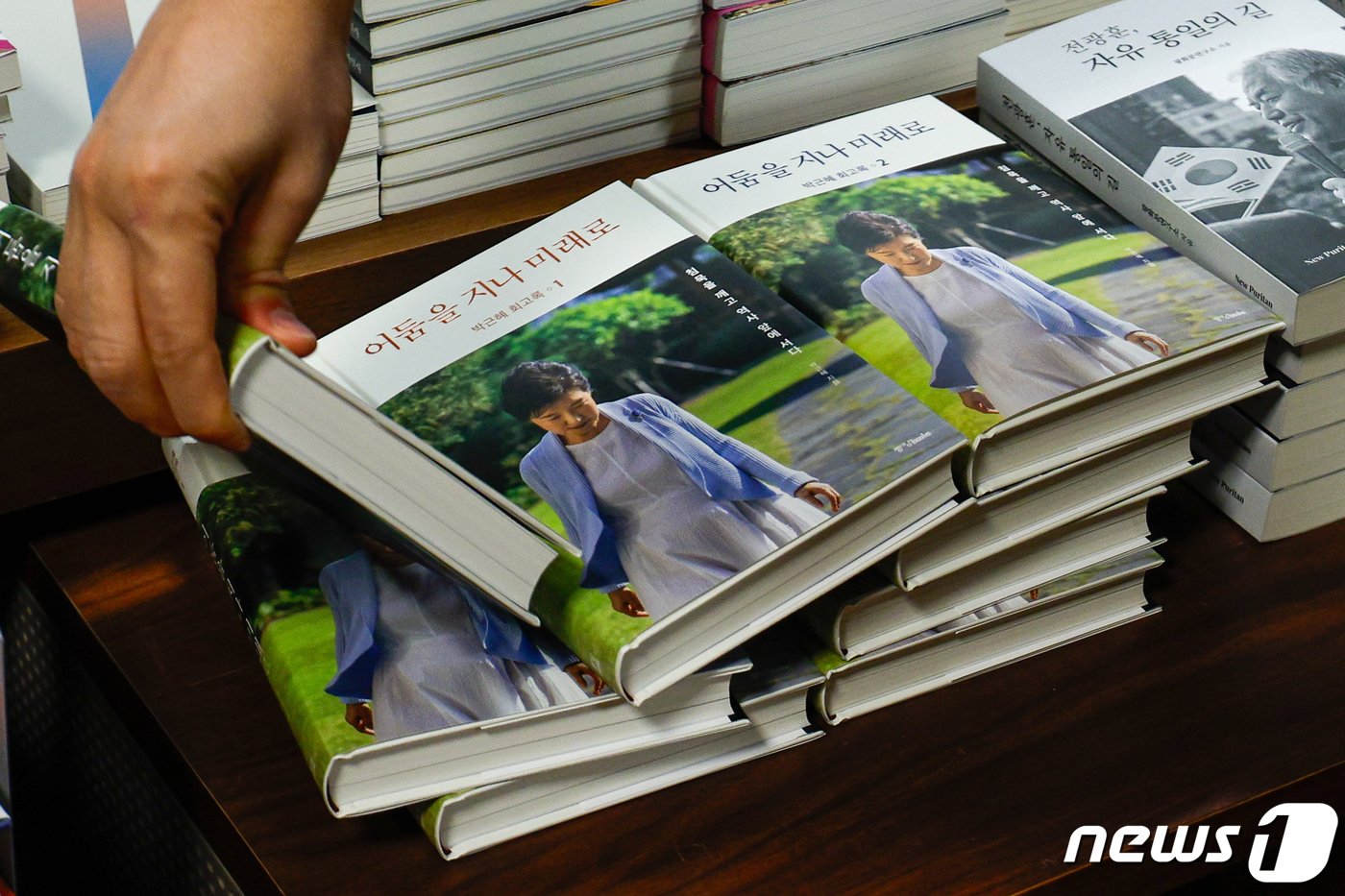 본문 이미지 - 박근혜 전 대통령이 제18대 대선 이후 사저로 내려오기 까지 약 10년에 걸친 이야기를 담은 회고록을 출간한 5일 서울 종로구 교보문고 광화문점에서 한 시민이 '박근혜 회고록: 어둠을 지나 미래로'를 집어들고 있다. 2024.2.5/뉴스1 ⓒ News1 안은나 기자