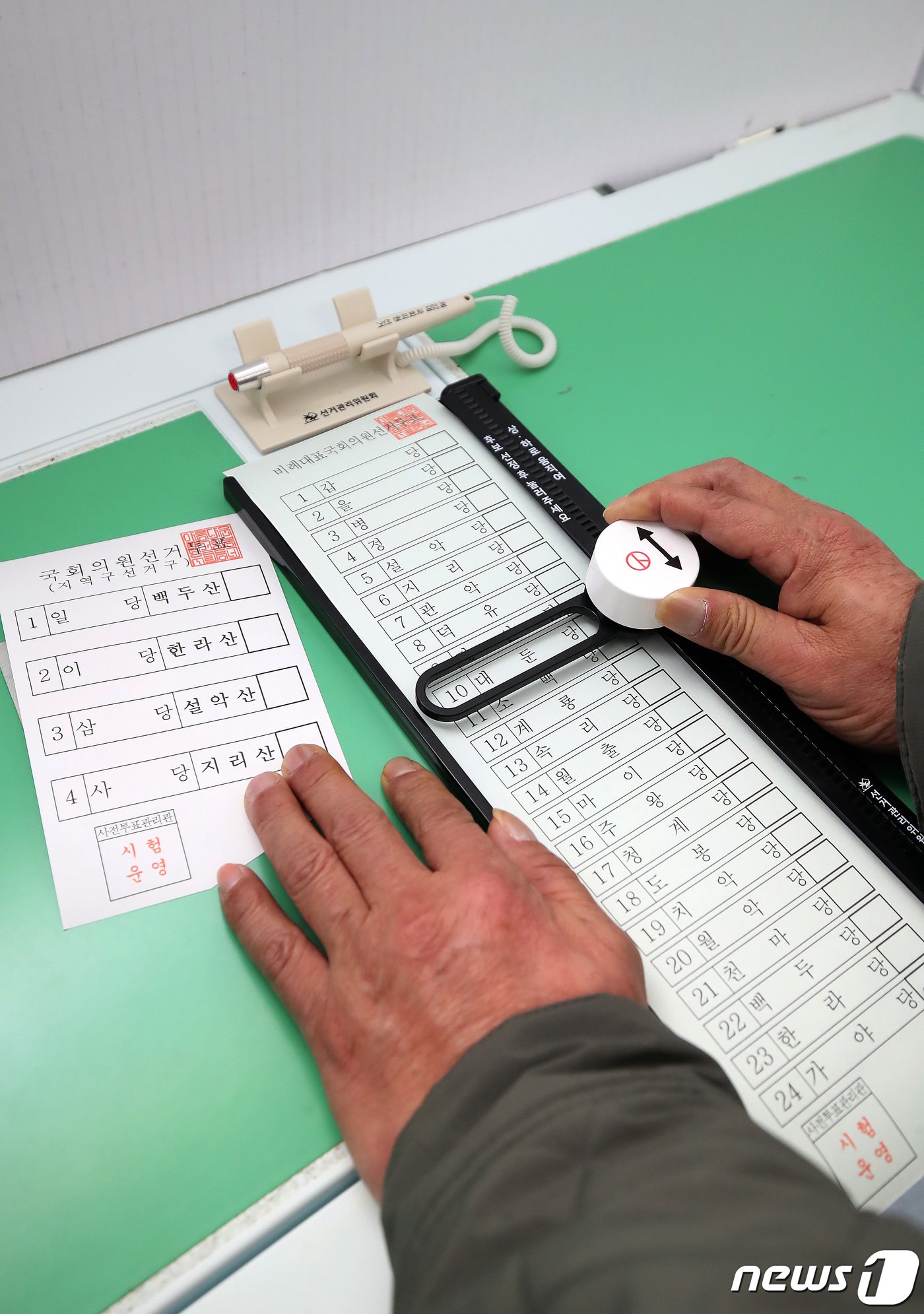 본문 이미지 - 4월 13일 실시되는 제20대 국회의원선거를 앞두고 13일 오후 대구 동구 장애인지역공동체에서 대구시선거관리위원회 주최로 열린 장애인유권자 모의 투표체험에서 한 유권자가 '레일 버튼형 특수 기표용구'를 이용해 기표하고 있다. 이번 선거부터 도입되는 이 기표용구는 원하는 기표 위치에 맞게 레일을 위아래 조정해 안전핀을 제거한 뒤 버튼을 누르면 기표된다. 발달장애인과 지체장애인 등 손떨림이 있거나 근력이 약한 장애인유권자가 편리하게 사용할 수 있도록 제작돼 사용 편의성과 사표 방지 등이 개선됐다는 평가를 받고 있다. 2024.3.13/뉴스1 ⓒ News1 공정식 기자