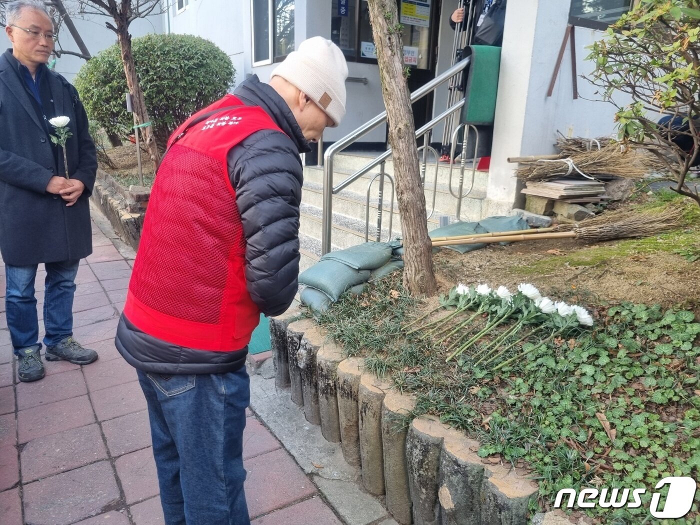본문 이미지 - 14일 노조원이 고인 박 씨가 투신한 대치동 선경아파트 앞 화단에 국화꽃을 헌화하고 묵례하고 있다.  