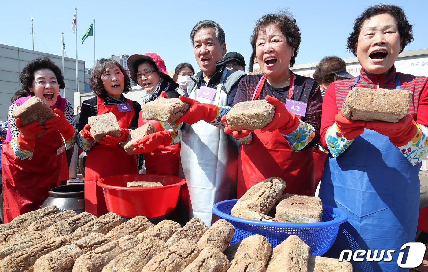 18일 오후 대구 달서구노인종합복지관 옥상에서 열린 &#39;달서구 어르신 장&#40;醬&#41; 담그기&#39; 행사에 참여한 어르신과 결혼이주여성 등 마을주민들이 장독대에 모여 장 담그기에 사용할 메주를 들어 보이며 환하게 웃고 있다. 2024.3.18/뉴스1 ⓒ News1 공정식 기자