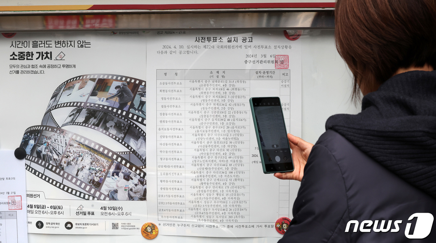 (서울=뉴스1) 김성진 기자 = 25일 서울 중구 을지로동 주민센터에 게시된 사전투표 4.10 제22대 국회의원 선거 사전투표소 설치 공고문을 한 시민이 촬영하고 있다.사전투표는 …