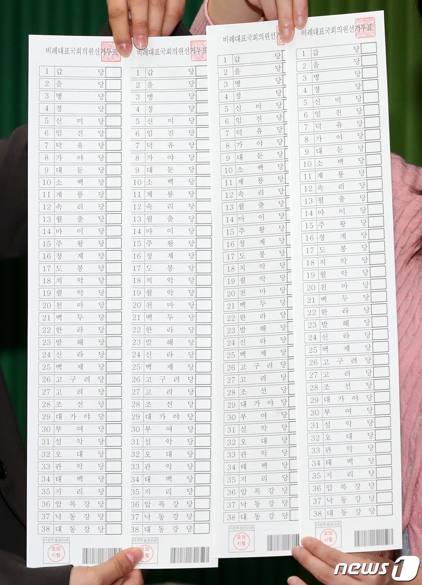 본문 이미지 - 26일 대전 중구 서대전초등학교에서 진행된 제22대 국회의원 선거 및 중구청장 재선거 대비 사전투표 모의시험에서 중구청 직원들이 비례대표 국회의원 선거 투표용지를 들어 보이고 있다. 2024.3.26 /뉴스1 ⓒ News1 김기태 기자