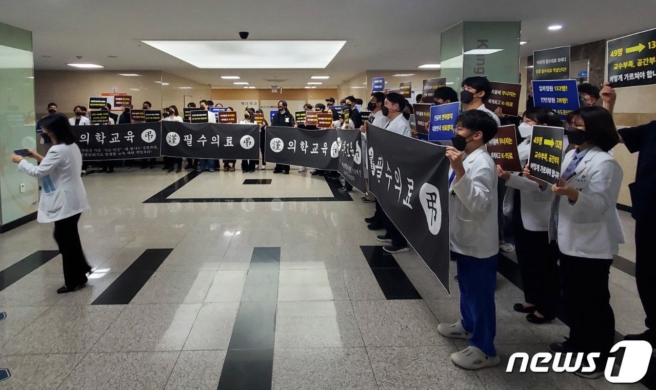 강원대학교 의과대학 교수, 전공의, 학생 40여 명이 27일 춘천 강원대병원 암센터 입구에서 이주호 교육부 장관의 현장간담회 시간에 맞춰 의과대학 정원 증원에 반대하는 피켓 들고 침묵시위를 벌였다. 이들은 검정색 마스크와 근조 리본을 달고 있었다.2024.3.27&#40;독자 제공&#41; ⓒ News1 한귀섭 기자