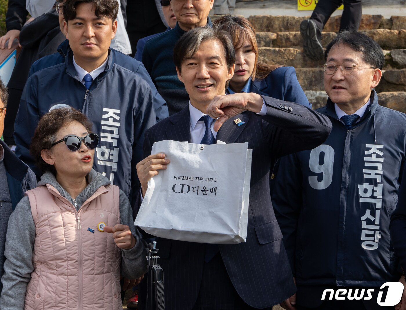 본문 이미지 - 조국 조국혁신당 대표가 31일 경남 거제시 김영삼 전 대통령 생가에서 한 지지자로부터 '외국회사의 작은 파우치 CD 디올백'이라고 적힌 가방을 들고 손으로 '기호9번'을 표현하고 있다. (조국혁신당 제공) 2024.3.31/뉴스1 ⓒ News1 송원영 기자