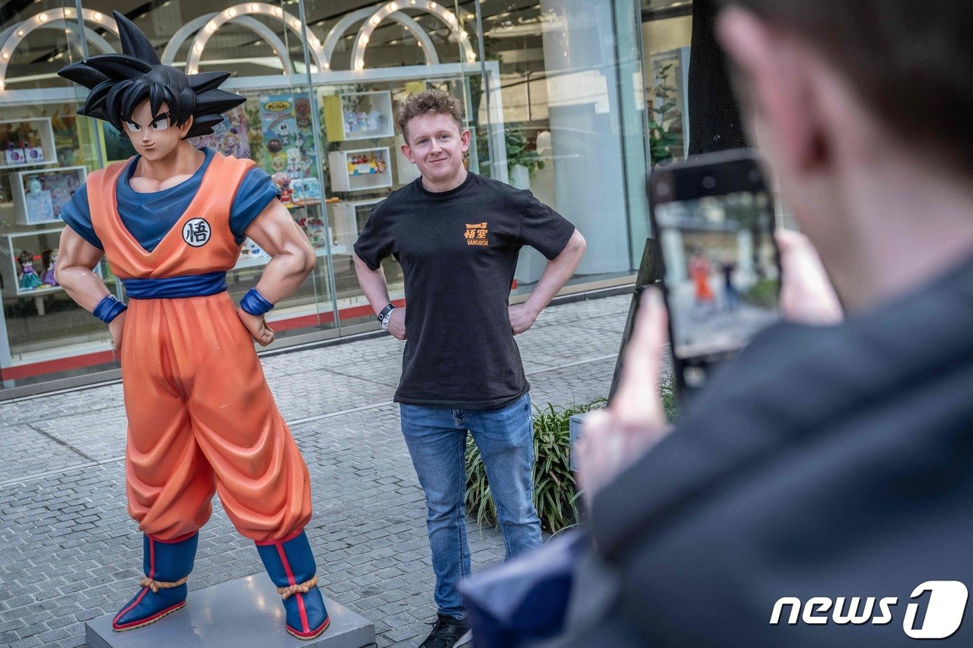 본문 이미지 - 8일 일본 도쿄에 세워진 만화 '드래곤 볼' 주인공, 손오공의 동상 옆에서 한 관광객이 드래곤 볼 티셔츠를 입고 같은 포즈를 취하고 있다. 2024.03.08/ ⓒ AFP=뉴스1 ⓒ News1 권진영 기자