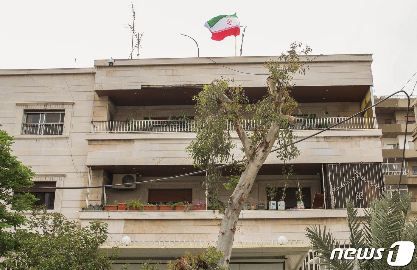 본문 이미지 - 8일(현지시간) 시리아 다마스쿠스 주재 이란 영사관 건물 위, 이란 국기가 펄럭이고 있다. 해당 영사관은 이달 1일 이스라엘의 공격을 받았다. 2024.04.08/ ⓒ 로이터=뉴스1 ⓒ News1 권진영 기자