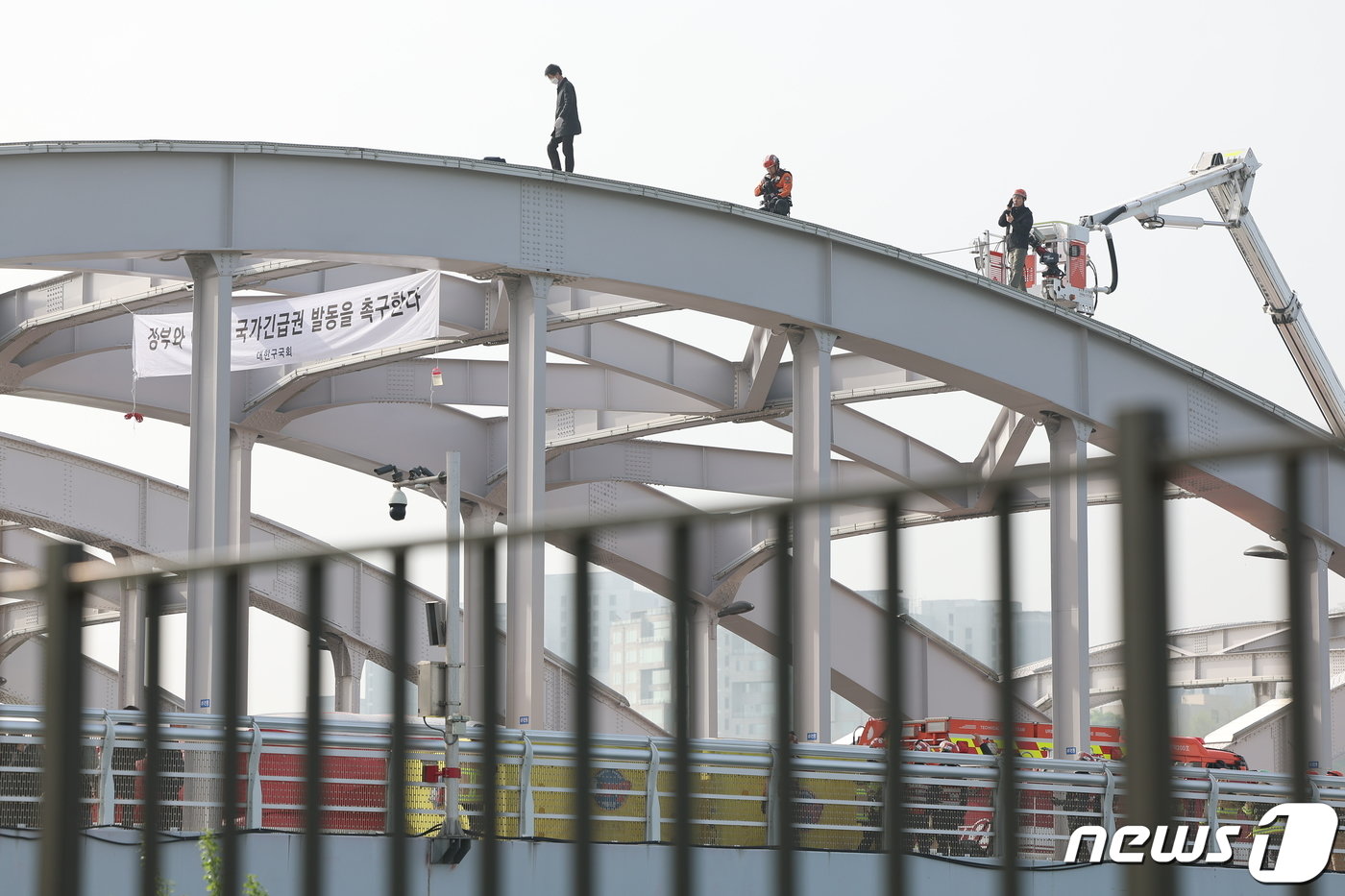 본문 이미지 - 17일 오전 서울 한강대교 노량진 방면에서 신원을 알 수 없는 남성이 교량 위에 올라가 소동을 벌이고 있다. 2024.4.17/뉴스1 ⓒ News1 김도우 기자