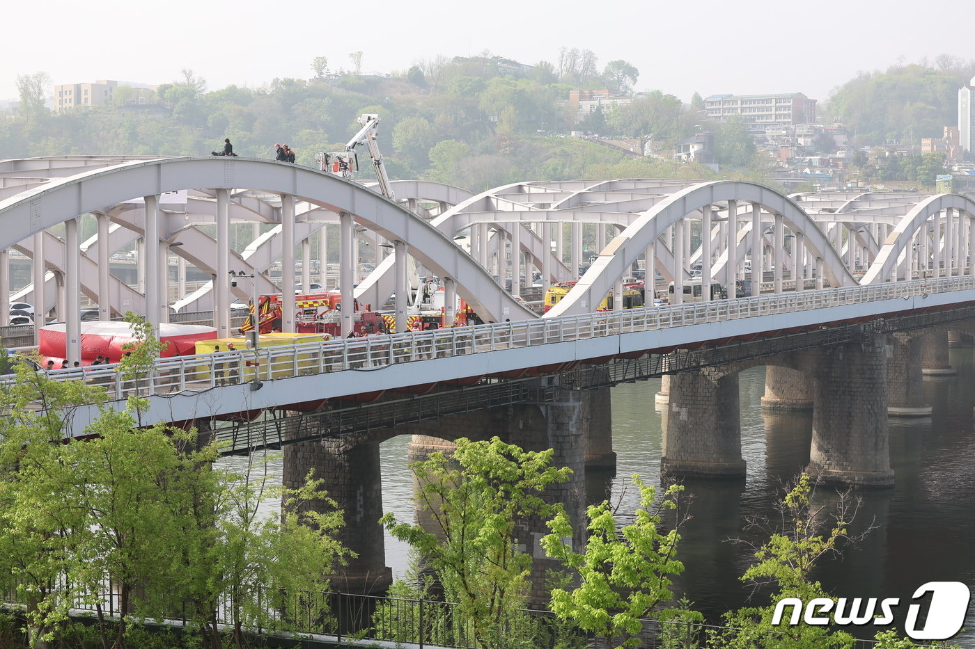 본문 이미지 - 17일 오전 서울 한강대교 노량진 방면에서 교량 위에 올라가 소동을 벌이고 있는 신원을 알 수 없는 남성을 현장에 출동한 소방대원들이 설득하고 있다. 2024.4.17/뉴스1 ⓒ News1 김도우 기자