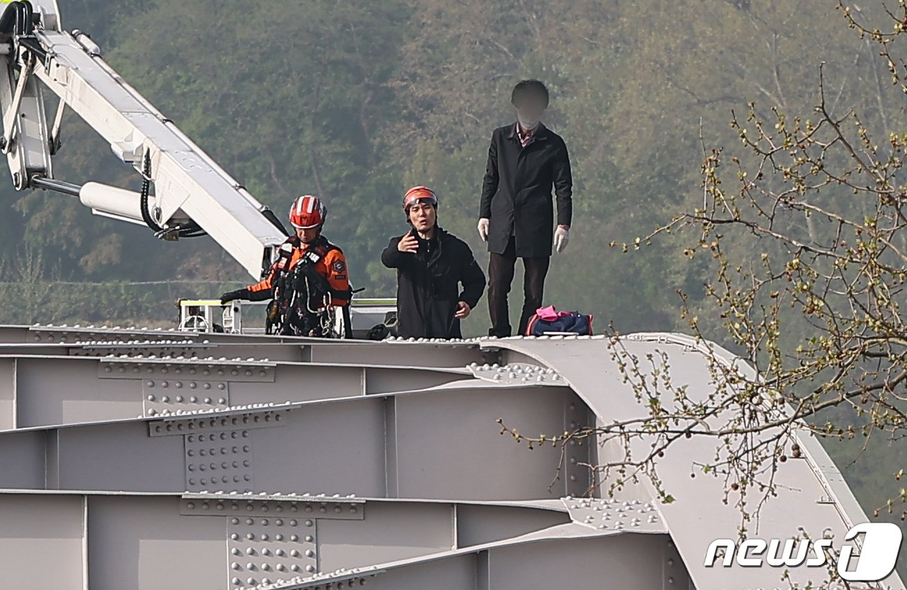 본문 이미지 - 17일 오전 서울 한강대교 노량진 방면에서 신원을 알 수 없는 남성이 교량 위에 올라가 소동을 벌이고 있다. 2024.4.17/뉴스1 ⓒ News1 김도우 기자
