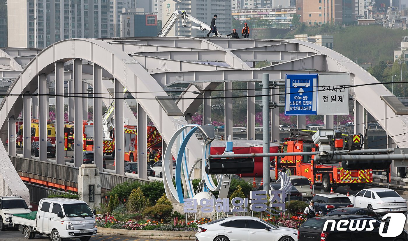 본문 이미지 - 17일 오전 서울 한강대교 노량진 방면에서 신원을 알 수 없는 남성이 교량 위에 올라가 소동을 벌이고 있다. 2024.4.17/뉴스1 ⓒ News1 김도우 기자