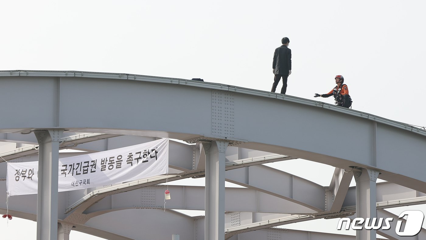 17일 오전 서울 한강대교 노량진 방면에서 교량 위에 올라가 소동을 벌이고 있는 신원을 알 수 없는 남성을 현장에 출동한 소방대원이 설득하고 있다. 2024.4.17/뉴스1 ⓒ News1 김도우 기자