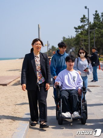 본문 이미지 - 연곡해변 캠핑장 보행로를 지체 장애인 여행자와 걷고 있는 장미란 문화체육관광부 제2차관(한국관광공사 제공)
