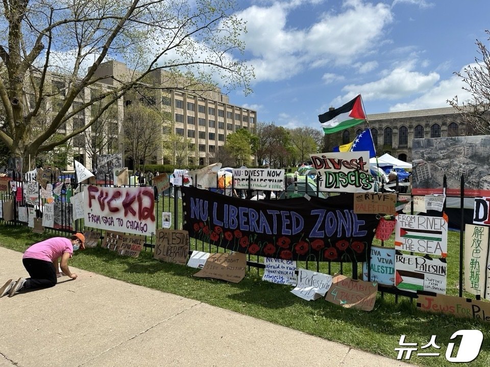 본문 이미지 - &#39;NU 자유구역&#40;NU LIBREATED ZONE&#41;&#39;이라고 적힌 플래카드 앞에서 한 시민이 바닥에 메시지를 적고 있다. ⓒ 뉴스1 박영주 통신원 2024.04.27/