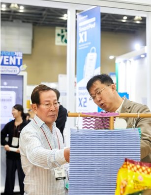 본문 이미지 - 24일 '2024 KOREA PACK & ICPI WEEK'가 열린 킨텍스 전시장을 찾은 교촌그룹 권원강 회장(왼쪽)이 케이앤엘팩 김범진 대표로부터 '바스락' 종이 완충재 기능에 대한 설명을 듣고 있다.(교촌에프앤비 제공)