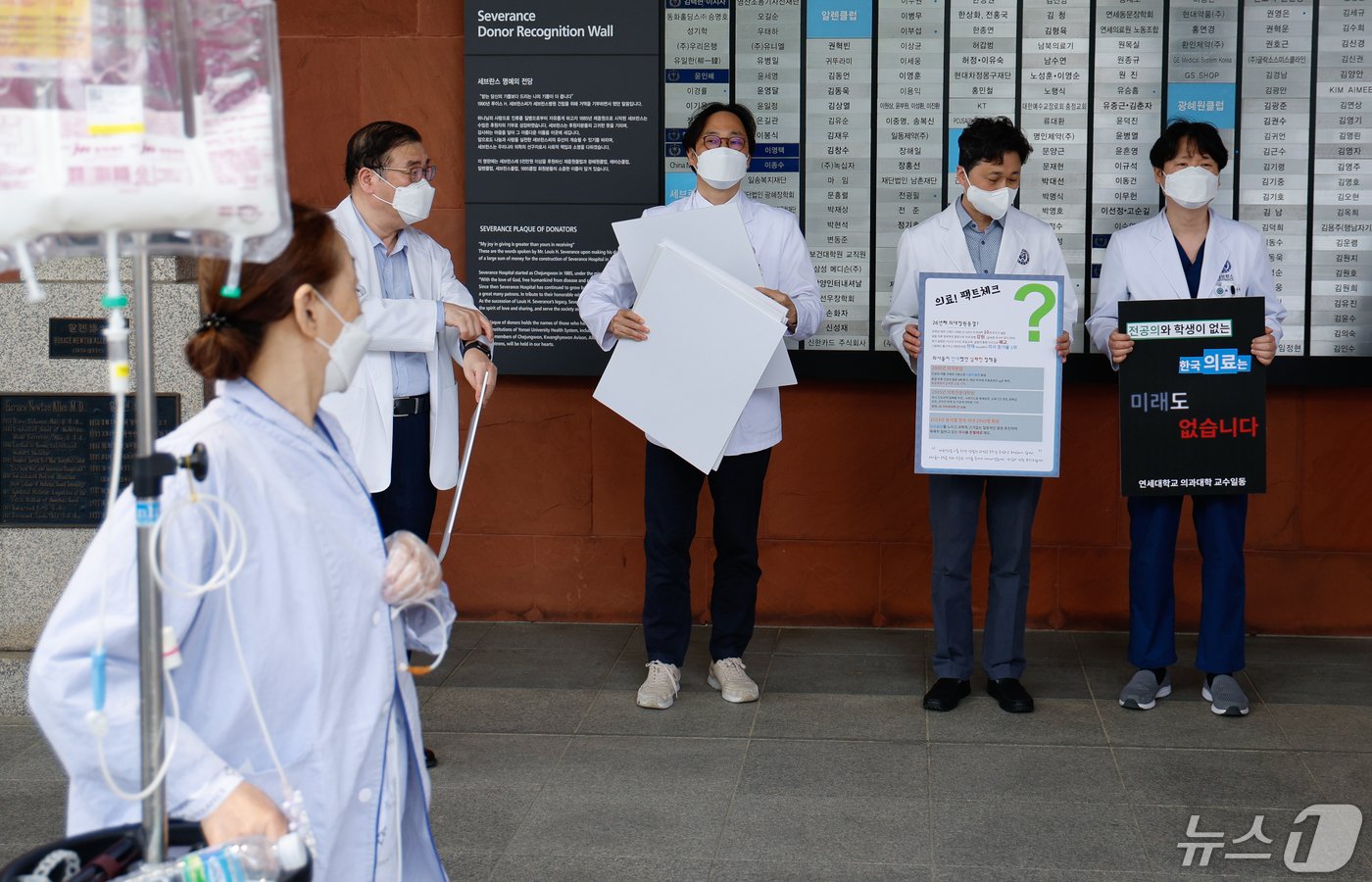 안석균 연세대학교 의과대학 비상대책위원장&#40;왼쪽 첫번째&#41;을 비롯한 교수들이 외래 진료 휴진에 들어간 30일 서울 서대문구 세브란스병원 본관 앞에서 의대정원 확대 등 정부 의료개혁 원점 재논의를 촉구하며 피켓 시위를 준비하는 가운데 한 환자가 이를 지켜보고 있다. 2024.4.30/뉴스1 ⓒ News1 안은나 기자