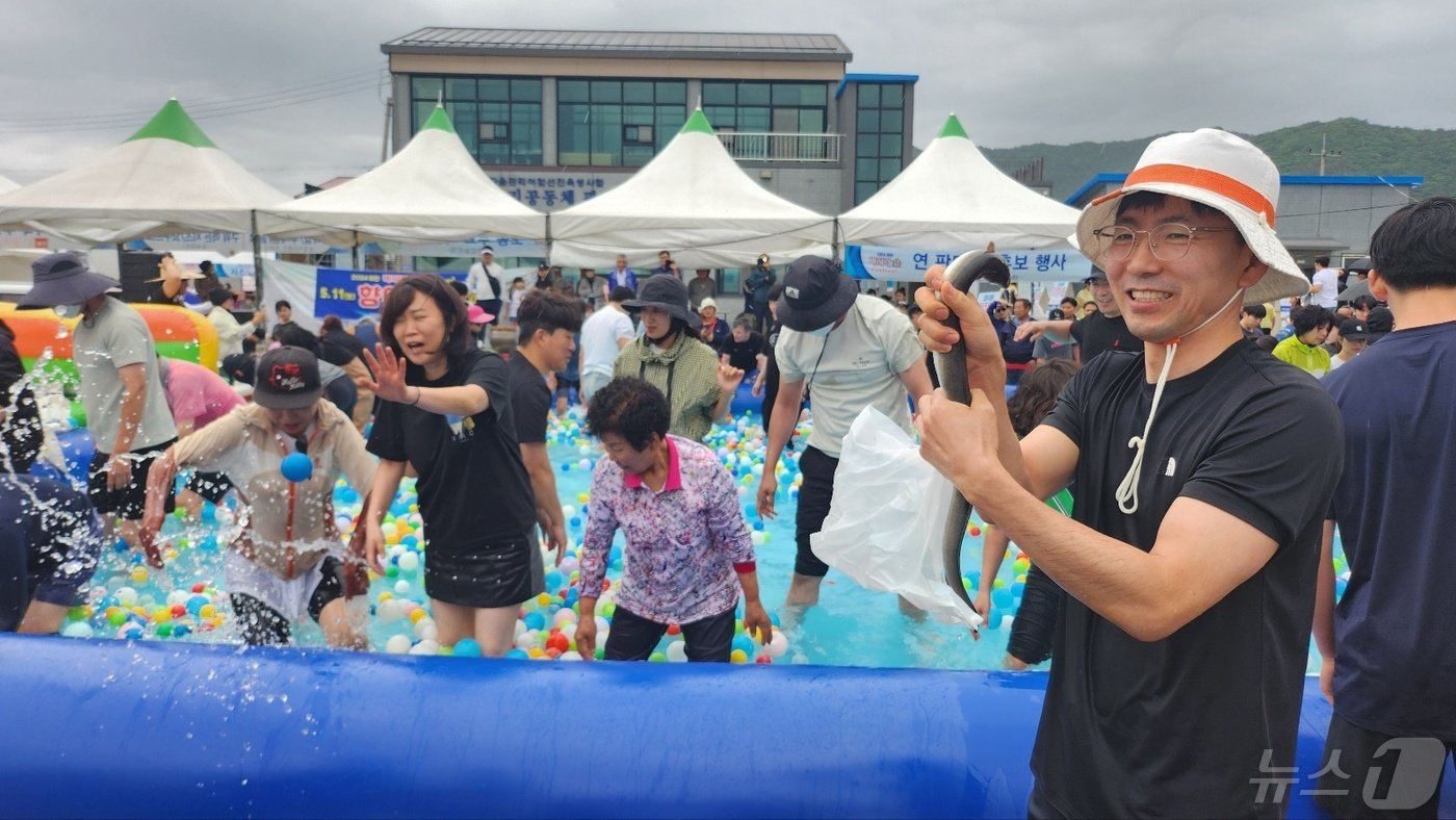 본문 이미지 -  '2024년 하전 바지락 오감체험 페스티벌(고창 바지락 축제)'에 참여한 관광객이 장어잡기 체험행사애서 장어를 잡고 기뻐하고 있다.(2024.5.12/ 뉴스1 ⓒ News1 박제철 기자