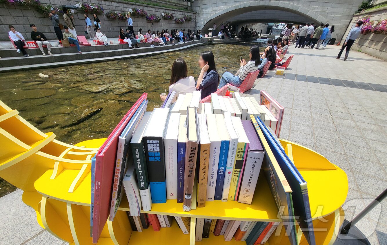 본문 이미지 - 서울 낮 최고 기온이 25도까지 오르며 초여름 날씨를 보인 17일 서울 청계천에서 열린 서울야외도서관-책 읽는 맑은 냇가에서 시민들이 의자에 앉아 책을 보며 휴식을 취하고 있다. 2024.5.17/뉴스1