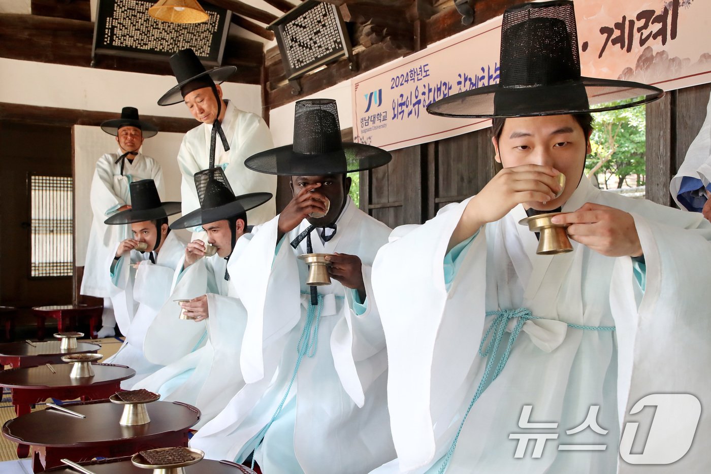 본문 이미지 - 성년의 날(20일·매년 5월 셋째 월요일)을 사흘 앞둔 17일 영남대학교 민속촌 구계서원에서 열린 '2024학년도 외국인 유학생과 함께하는 전통 성년식'에 참여한 남학생들이 술잔을 받아 조심스레 맛보고 있다. 2024.5.17/뉴스1 ⓒ News1 공정식 기자