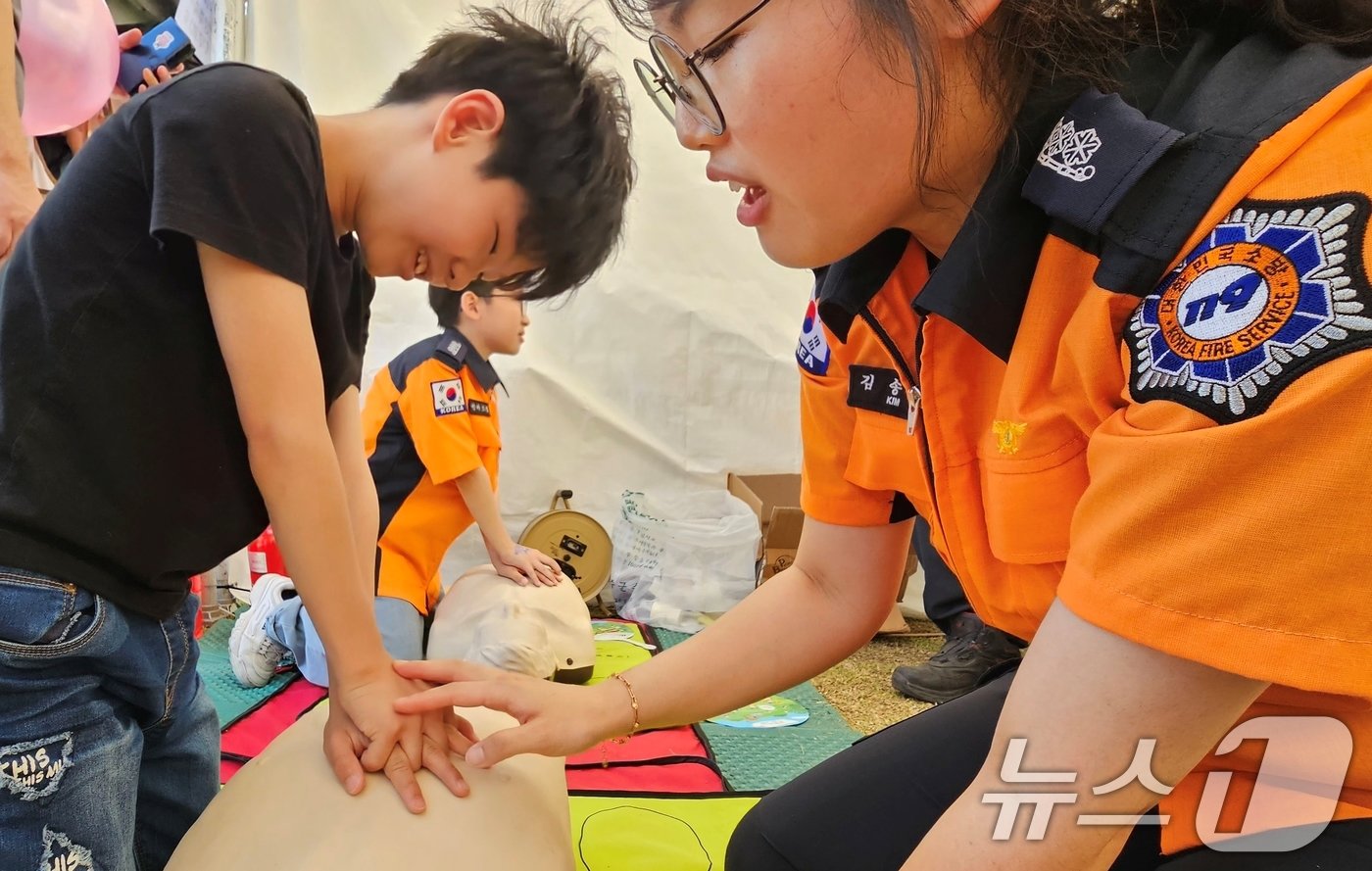 본문 이미지 - 18일 성주 성밖숲에서 열린 '2024 성주생명·참외문화축제장 소방관 체험코너에서 한 어린이가 심폐소생술 체험을 하고 있다. 2024.5.18/뉴스1 ⓒ News1 정우용 기자