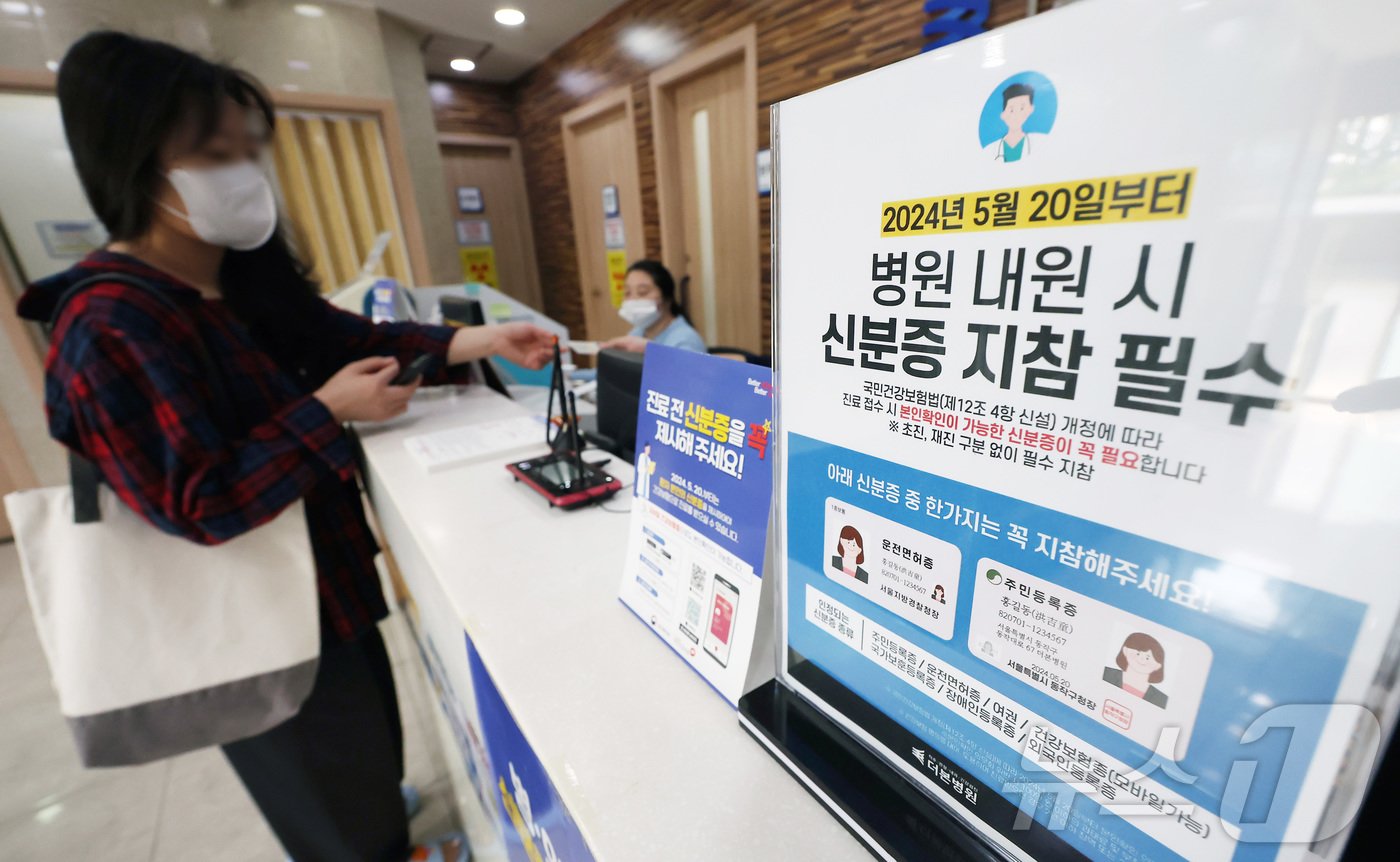 본문 이미지 - 건강보험 본인확인 의무화 제도가 시행된 20일 오전 서울 동작구 한 병원에서 시민이 접수를 하며 신분증을 보여주고 있다.  2024.5.20/뉴스1 ⓒ News1 김민지 기자