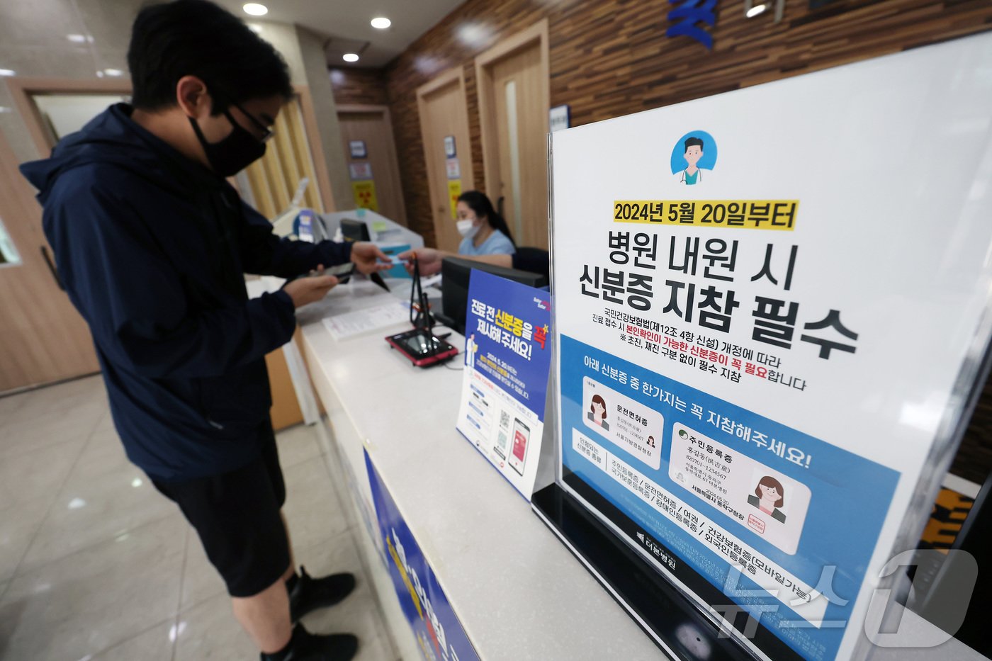 본문 이미지 - 건강보험 본인확인 의무화 제도가 시행된 20일 오전 서울 동작구 한 병원에서 시민이 접수를 하며 신분증을 보여주고 있다.  2024.5.20/뉴스1 ⓒ News1 김민지 기자