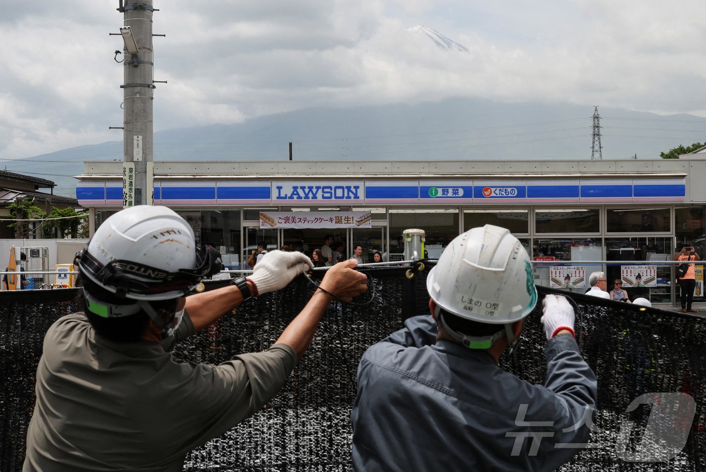 본문 이미지 - 21일 일본 야마나시현 후키가와구치코 마을의 한 편의점 인근에서 인부들이 시야를 가리기 위한 가림막을 설치하고 있다. 2024.05.21/ ⓒ 로이터=뉴스1 ⓒ News1 권진영 기자